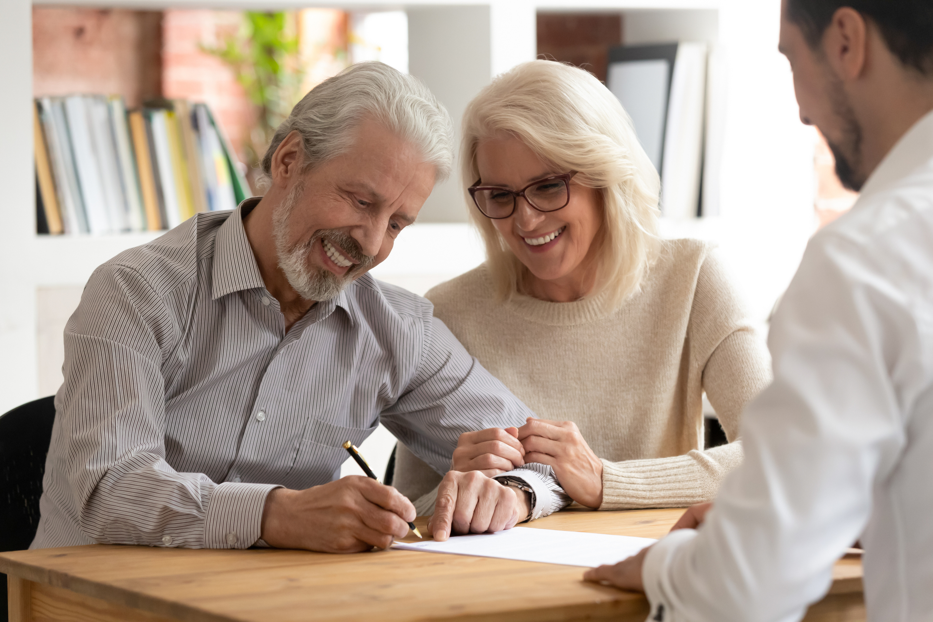 Happy older couple clients sign insurance contract meeting agent